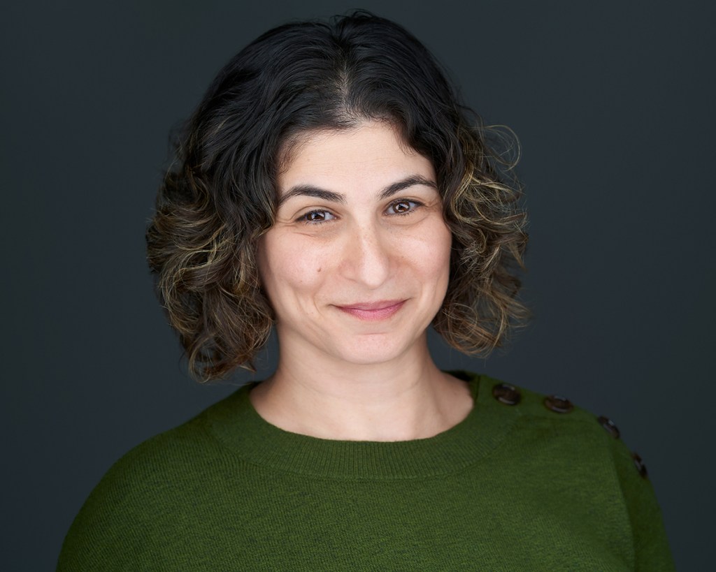 image of Jaclyn Greenberg smiling, with  brown curly hair and brown eyes.