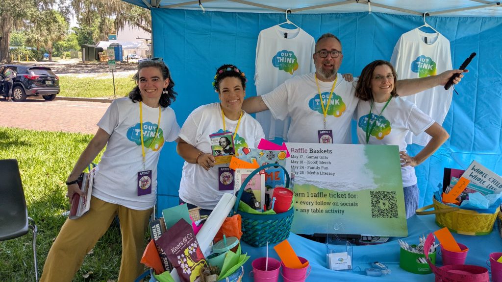 photo of four people in OUt Think Media t-shirts at an activity table